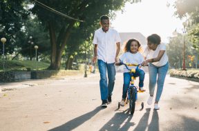 man-standing-beside-his-wife-teaching-their-child-how-to-1128318