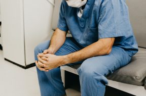 man-wearing-blue-scrub-suit-and-mask-sitting-on-bench-3279197