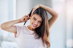 Portrait of a beautiful young woman brushing her hair in the bathroom at home