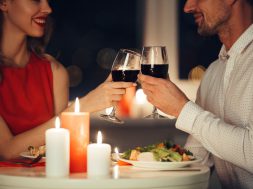 Cropped photo of young lovers having romantic dinner and drinking red wine at home