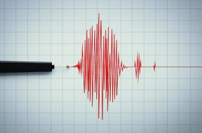 Seismograph recording seismic activity on grid paper. Horizontal composition with copy space. Earthquake concept.