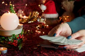 Blurred Tarot cards on table near burning candles. Tarot reader or Fortune teller reading on Christmas decoration