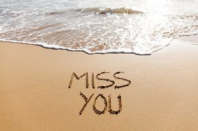 MIss you written in the sand on a beach.