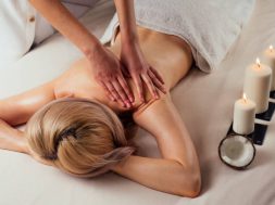 Ayurvedic relaxing.health beauty happy blonde woman in spa salon getting massage .Beautiful girl enjoying day spa resort, lying down on the table treatment procedure next to the candle fire