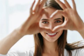 Healthy Eyes And Vision. Portrait Of Beautiful Happy Woman Holding Heart Shaped Hands Near Eyes. Closeup Of Smiling Girl With Healthy Skin Showing Love Sign. Eyecare. High Resolution Image