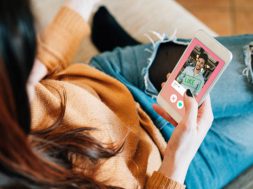 Young adult woman swiping on an online dating app. She's using her smart phone on the sofa at home.