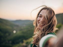 One woman, portrait of a young female hiker taking a selfie high on mountain in sunset.