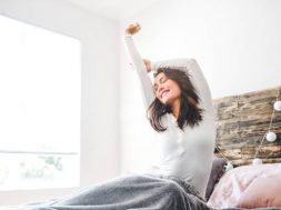 Cropped shot of a young woman stretching while sitting in her bed