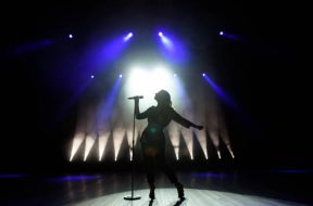 Silhouette of singer on stage. Dark background, smoke, spotlights